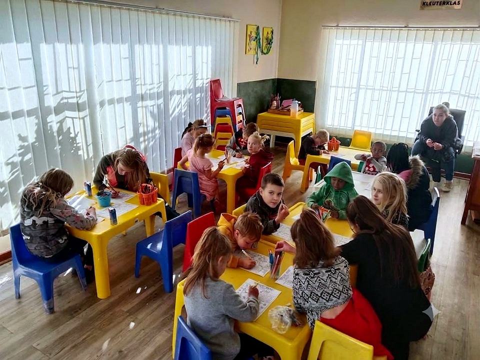 Kinders teken en kleur by klein geel tafels in die kinderkerk